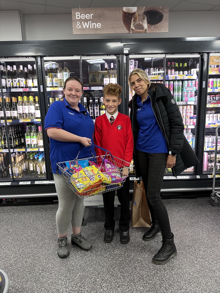 Dexter holding a basket overflowing with sweets and snacks in a supermarket aisle