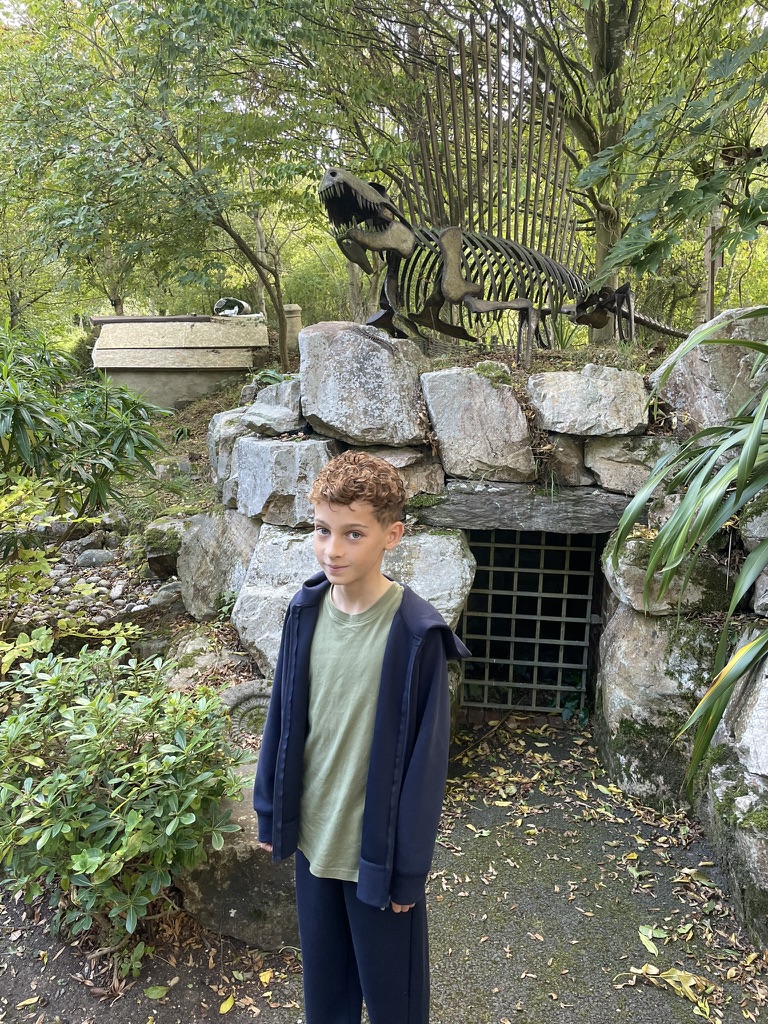 Dexter in front of the metal dinosaur skeleton sculpture in the hospice grounds