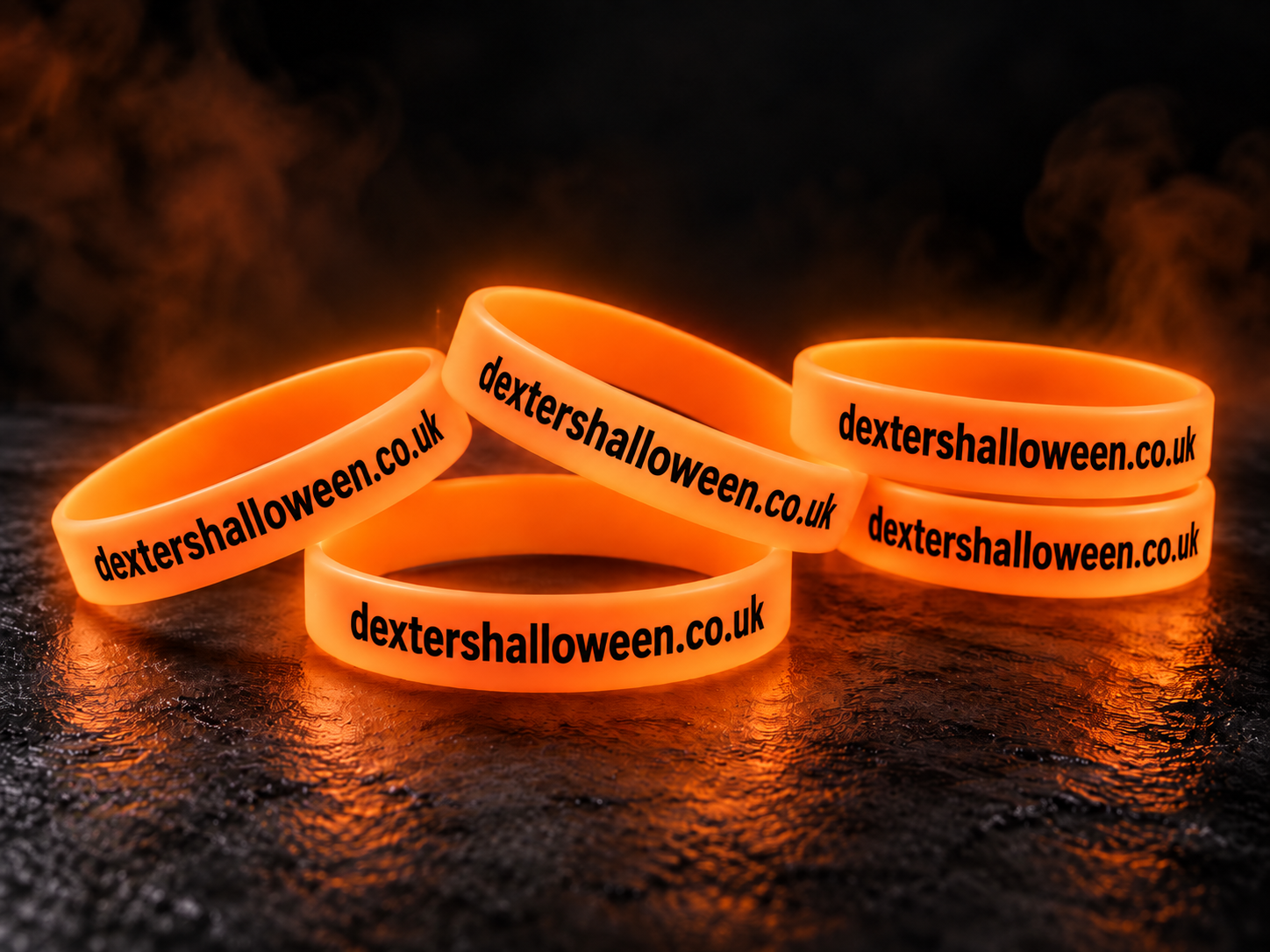 Five orange glow-in-the-dark Dexter's Halloween wristbands printed with dextershalloween.co.uk, glowing in the dark
