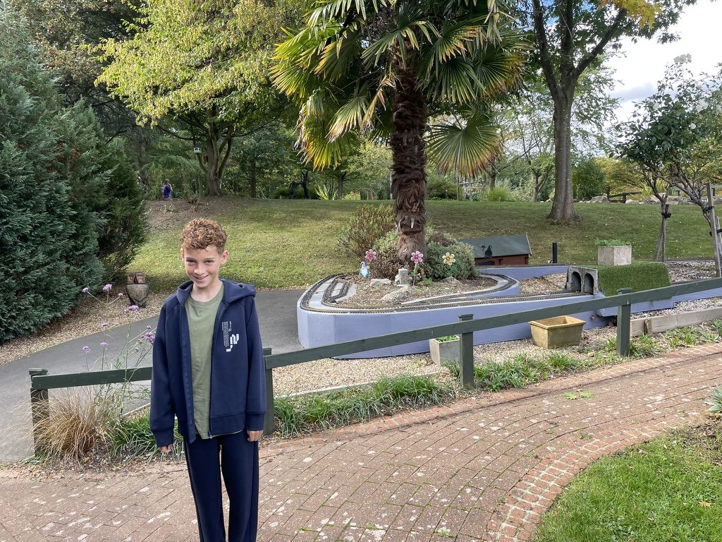 Dexter on the brick path in the hospice garden with the model railway behind him
