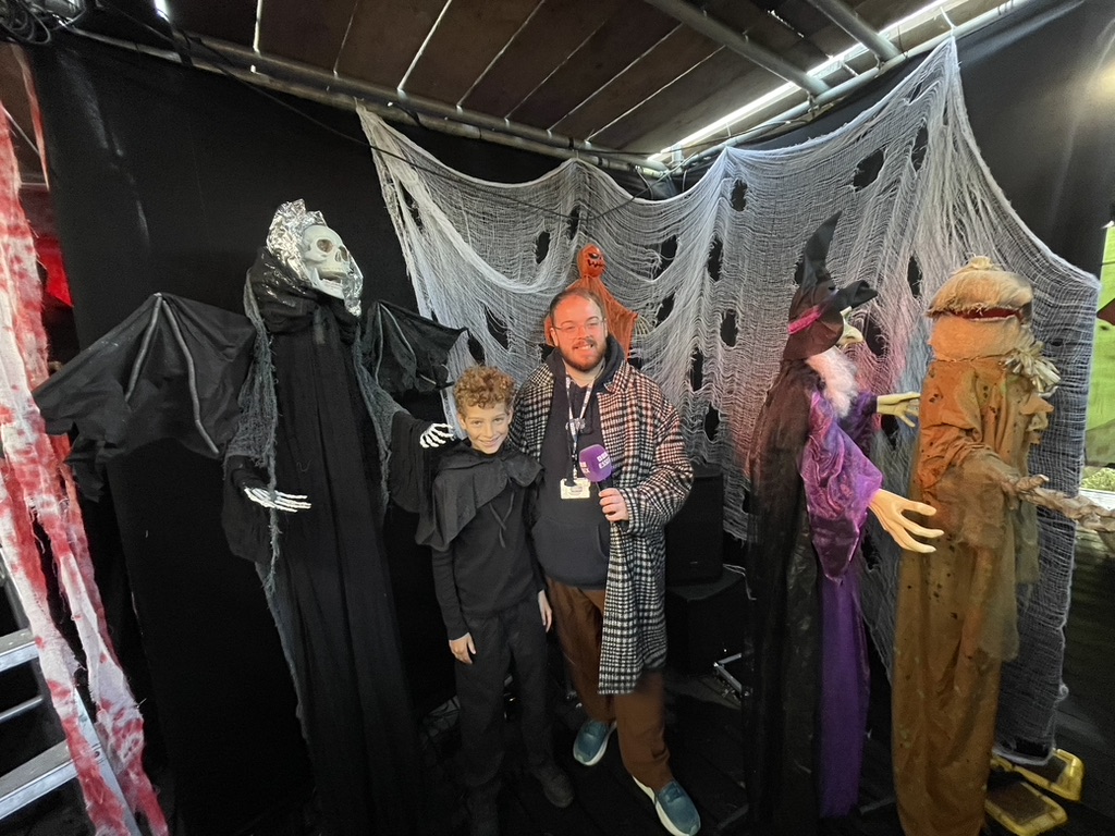 Dexter in a hooded costume being interviewed by BBC Essex among the Halloween decorations